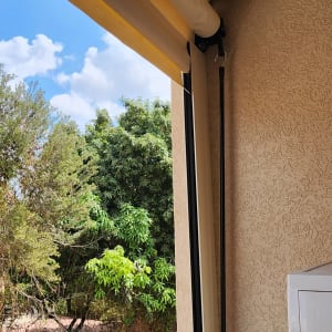 סוכך צהוב עם מנגנון גלילה על מרפסת