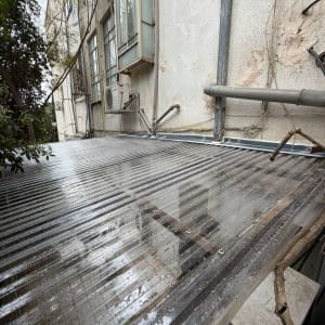 גג פלסטיק שקוף עם צינורות ליד קיר בניין