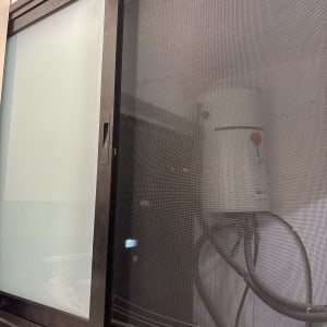 חלון אלומיניום עם רשת ומיכל מים ברקע