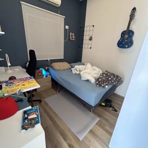 חדר שינה עם מיטה, גיטרה על הקיר ומזגן