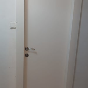 דלת לבנה עם ידית מתכת על קיר לבן