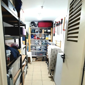 מדפים עם קופסאות פלסטיק, כלים תלויים על הקיר