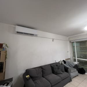 מזגן מותקן על קיר בסלון עם ספה ושולחן