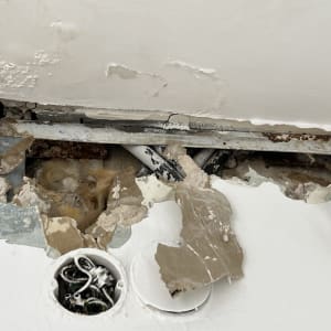 נזק לקיר עם צינורות חשופים ותקרה מתקלפת