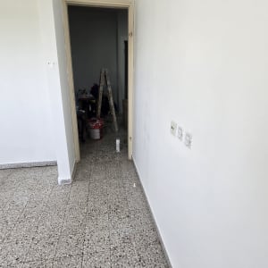 סולם ודלי צבע בחדר ריק עם קירות לבנים