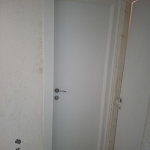 דלת לבנה עם ידית כסופה על קיר לבן