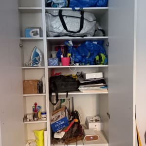 ארון עם תיקים, קופסאות, מגהץ ומוצרי ניקוי