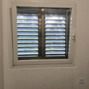 חלון עם תריסים מותקנים על קיר לבן