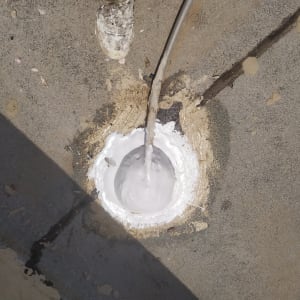 חומר איטום לבן סביב צינור על משטח בטון