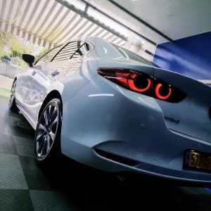 מכונית לבנה עם פנסים אחוריים דולקים במוסך