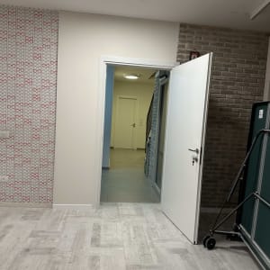 דלת פתוחה בחדר עם קיר לבנים ורצפת עץ אפורה