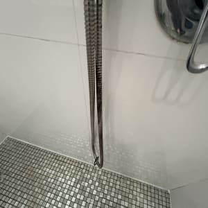 מקלחת עם רצפת אריחים וראש מקלחת מתכתי