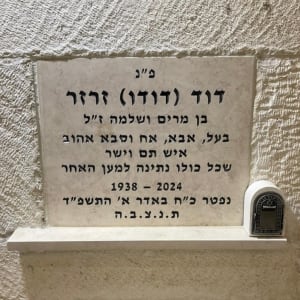 מצבה עם כיתוב בעברית ותמונה של נר זיכרון