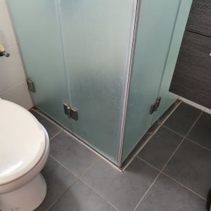 מקלחון זכוכית עם דלתות מתכת בחדר אמבטיה