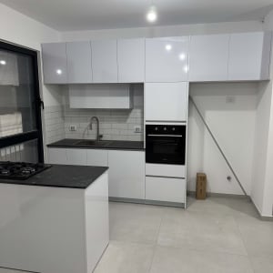 מטבח מודרני עם ארונות לבנים וכיריים שחורים