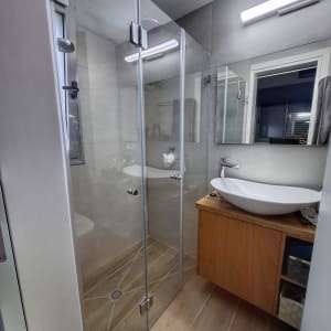 מקלחון זכוכית עם ראש מקלחת עגול ומדף קטן