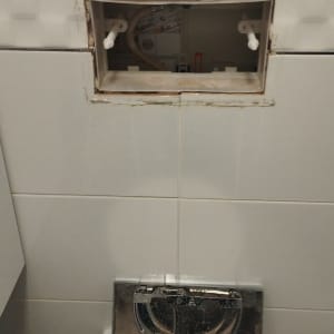פירוק לחצן ניאגרה סמויה בקיר במהלך תיקון מנגנון הניאגרה