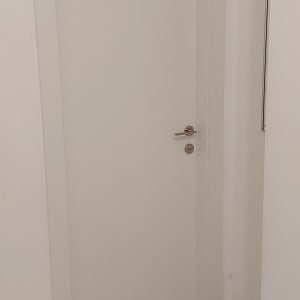 דלת לבנה עם ידית מתכת על רצפת אריחים