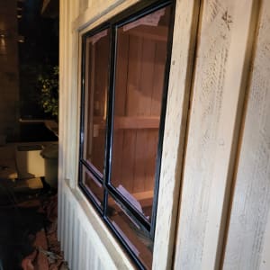 חלון זכוכית עם מסגרת שחורה בקיר עץ