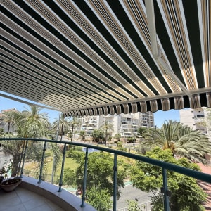 מרפסת עם סוכך בד פסים ונוף עירוני