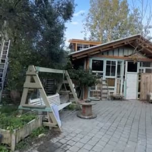 חצר עם נדנדה ומבנה עץ ברקע