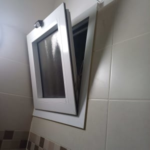 חלון אלומיניום פתוח עם מסגרת לבנה