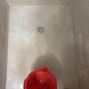 רצפת מקלחת עם דלי אדום ועבודת ריצוף חדשה