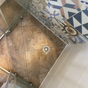 מקלחון פינתי עם דלתות הזזה מזכוכית, ריצוף דמוי עץ וחיפוי קירות מעוצב