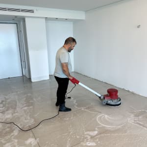 אדם מנקה רצפה עם מכונת פוליש אדומה