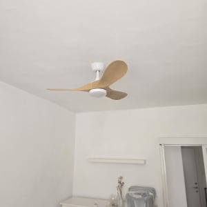 מאוורר תקרה בחדר עם קיר לבן ורהיטים.