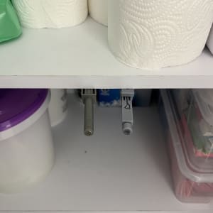 מדף עם גלילי נייר טואלט וכלי פלסטיק