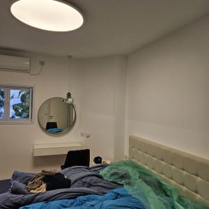 חדר שינה עם קיר צבוע בלבן ויריעת פלסטיק ירוקה