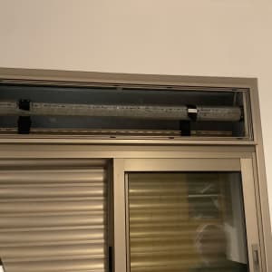 תריסים וחלון עם מנגנון פתיחה על קיר לבן