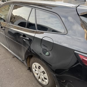 חלון אחורי של רכב שחור עם השתקפות בניינים