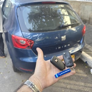 מפתחות רכב ביד ליד מכונית חונה ברחוב