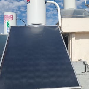 דוד שמש עם קולטים על גג תחת שמיים כחולים