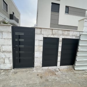 שערי אלומיניום שחורים על קיר אבן לבן