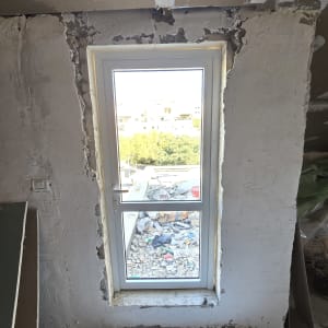 חלון אלומיניום מותקן בקיר בטון עם טיח מתקלף