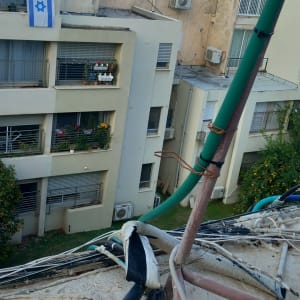 כבלים חשמליים על גג בניין עם צינורות ירוקים