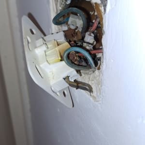 חוטי חשמל חשופים בקיר עם מתג חשמלי