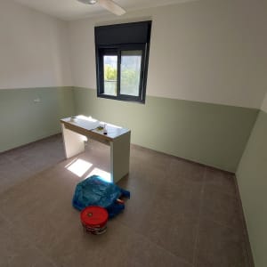 חדר צבוע בשני גוונים עם דלי צבע על הרצפה