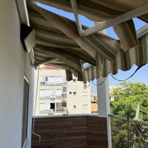 סוכך פסים תלוי מעל מרפסת עם נוף לעצים