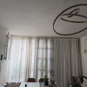 חדר עם שולחן, כיסאות וצמחים ליד חלון עם וילונות