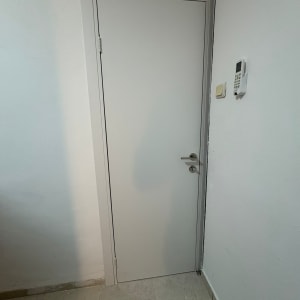 דלת לבנה עם ידית מתכת על קיר לבן