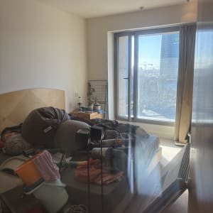 חדר מבולגן עם כלי ניקוי ודלי על המיטה