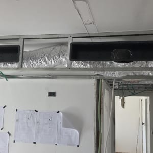 תעלות מיזוג אוויר מותקנות בתקרה עם תוכניות בנייה על הקיר