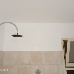 קיר צבוע עם מקלחת וחלון פתוח