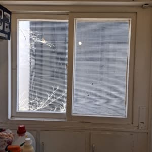 חלון עם תריסים ומוצרי ניקוי על מדף