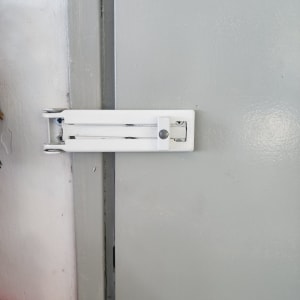 בריח מתכת לבן מותקן על דלת אפורה