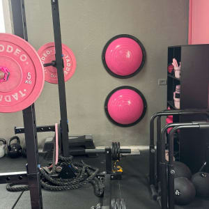 חדר כושר עם ציוד ורוד ושחור, משקולות, חבלים, כדורים